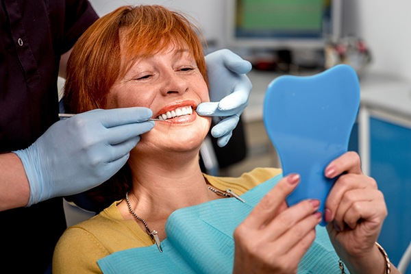 An aging woman admiring her new dental implant