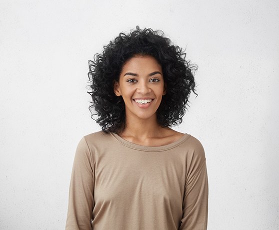 Woman in light brown shirt standing and smiling