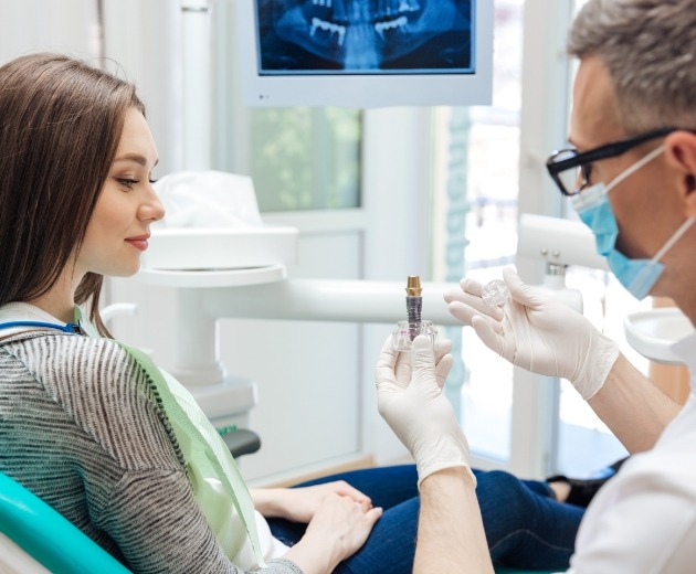 Oral surgeon showing a dental implant to a patient