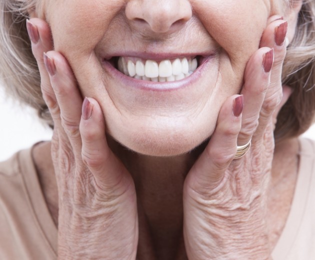 Smiling senior woman holding the sides of her cheeks