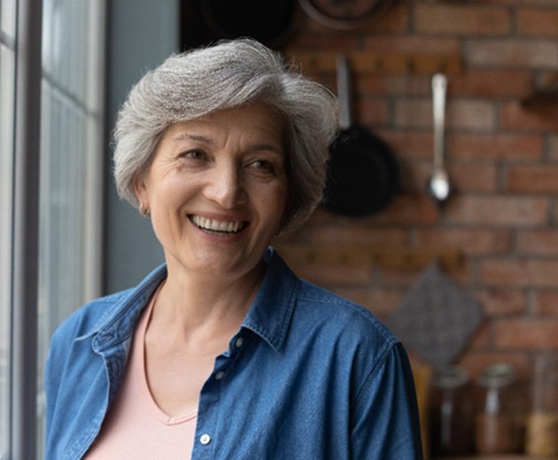 Woman smiling by a window with all-on-4 dental implants