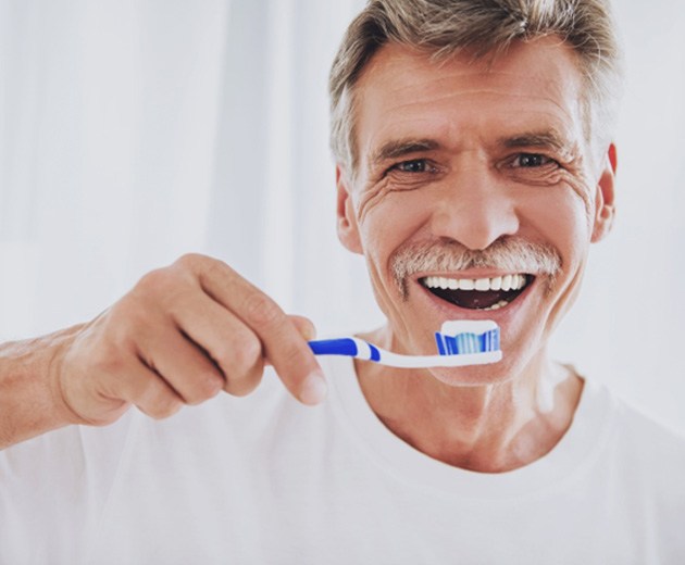 Man with all-on-4 dental implants brushing his teeth