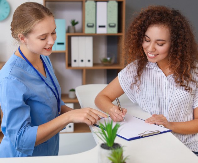 A patient filling out forms at a front desk