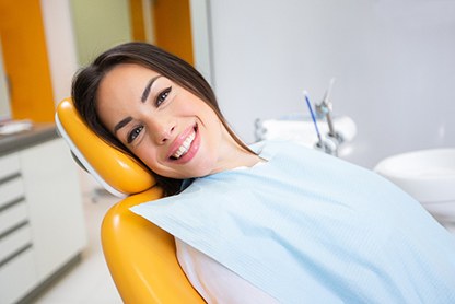 Female patient sitting back in chair at oral surgeon’s office and smiling