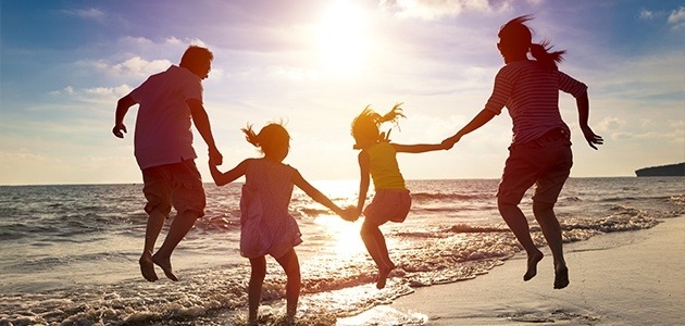 Family of four jumping on the beach at sunset