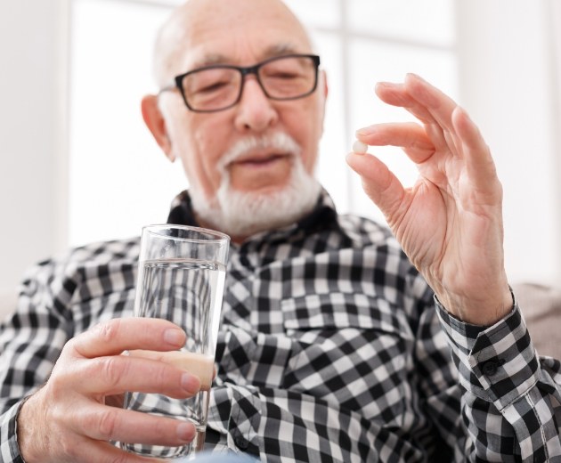 Senior man taking a pill for oral sedation in Burke