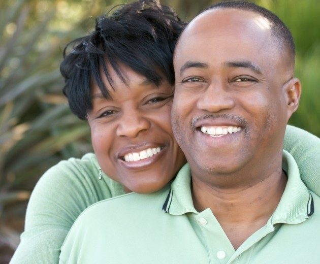 Man and woman in light green shirts smiling together outdoors