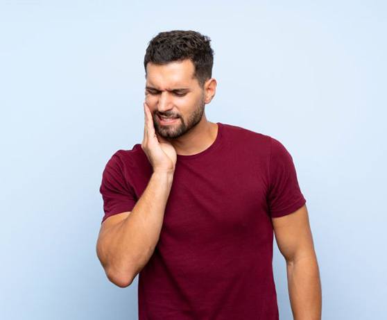 Man in burgundy t-shirt, experiencing mouth pain