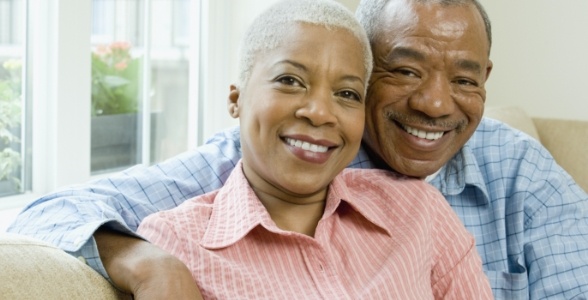 Man and woman smiling on couch after oral surgery services in Burke