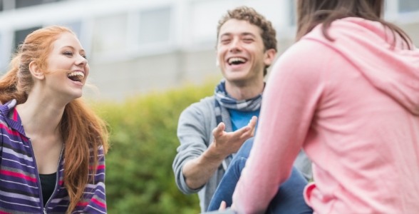 Three teenagers laughing together outdoors