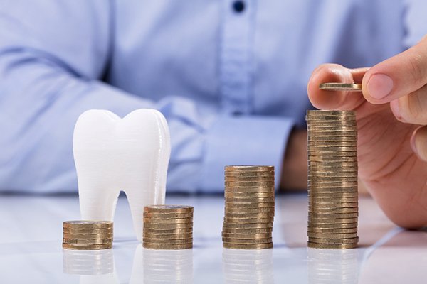 Someone piling coins next to a tooth