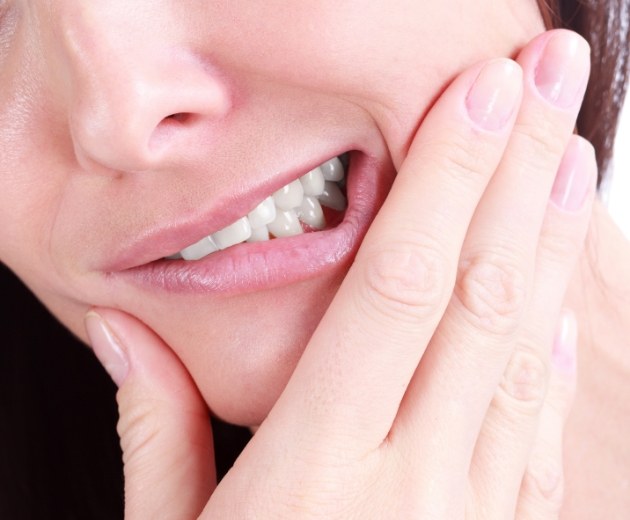 Close up of a person holding their cheek in pain before wisdom teeth extractions in Burke