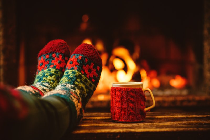 a person with festive socks sitting by a fireplace